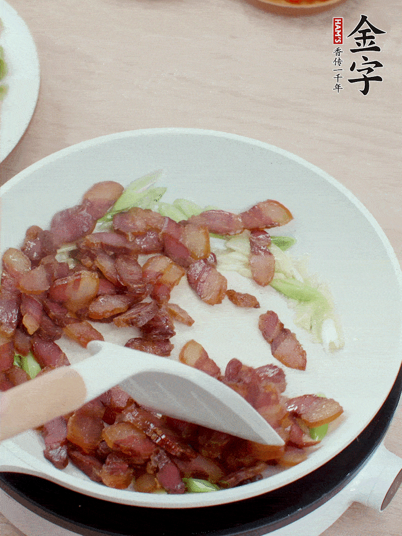 锅中少许油，姜、蒜白爆香，下腊肉煸出油脂。